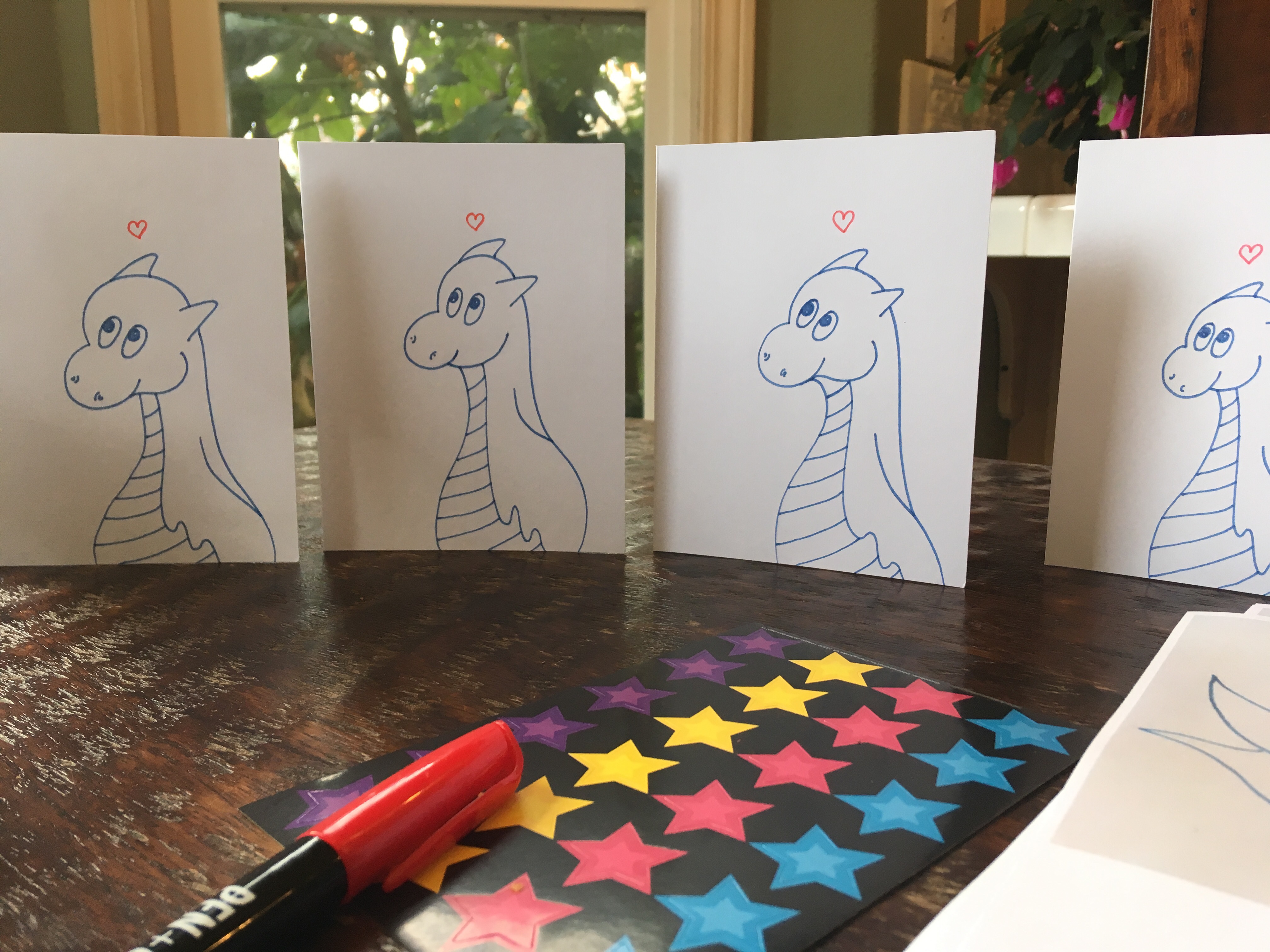 Front of several dragon cards with hearts on brown dining table